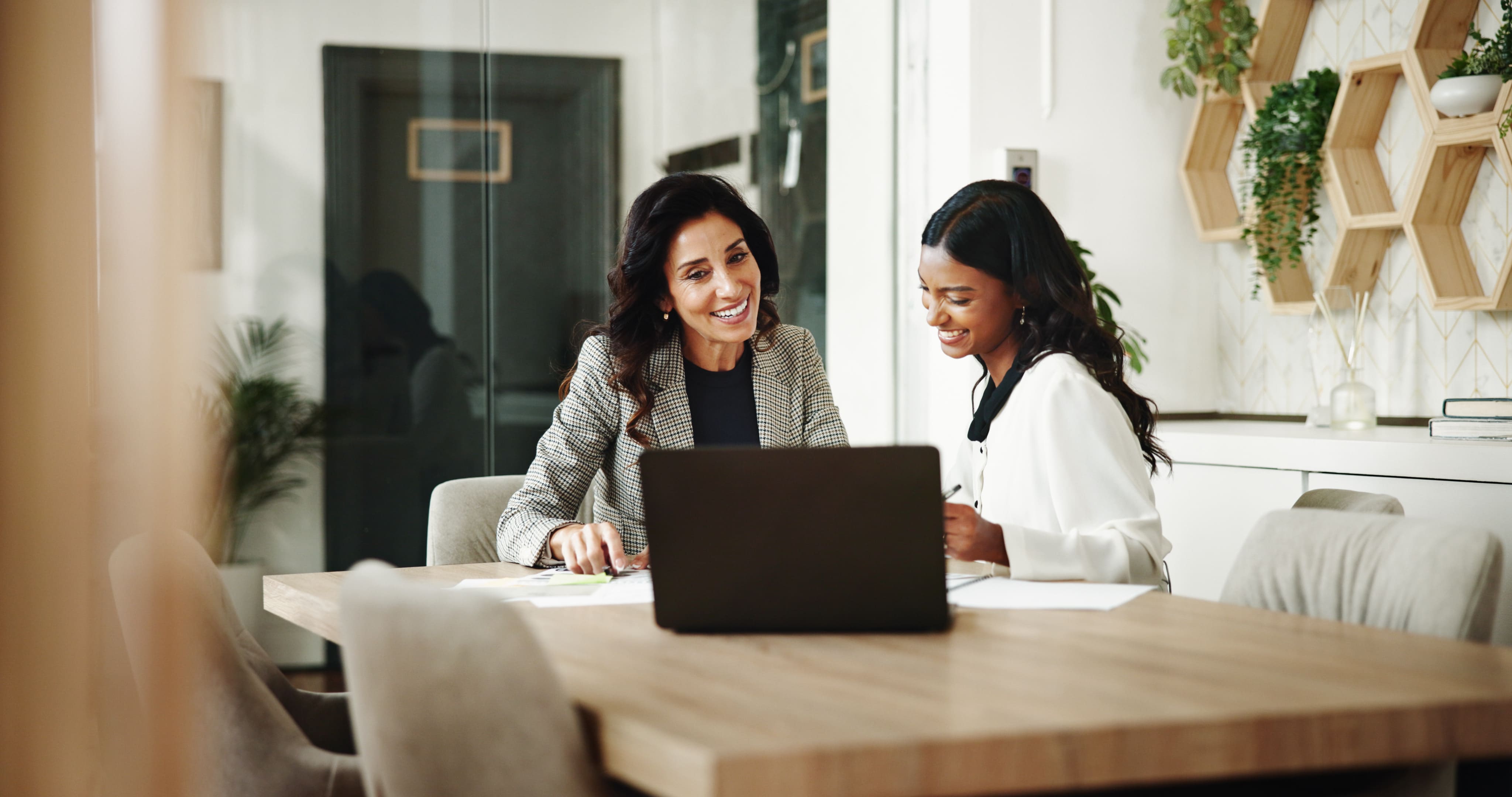 Two business professionals collaborating on a laptop in a modern office